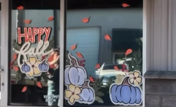 Happy Fall window painting with pumpkins and flowers at Party Place by Katie Paige Art Co